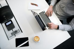 Businessman typing on a laptop with coffee on a conference table